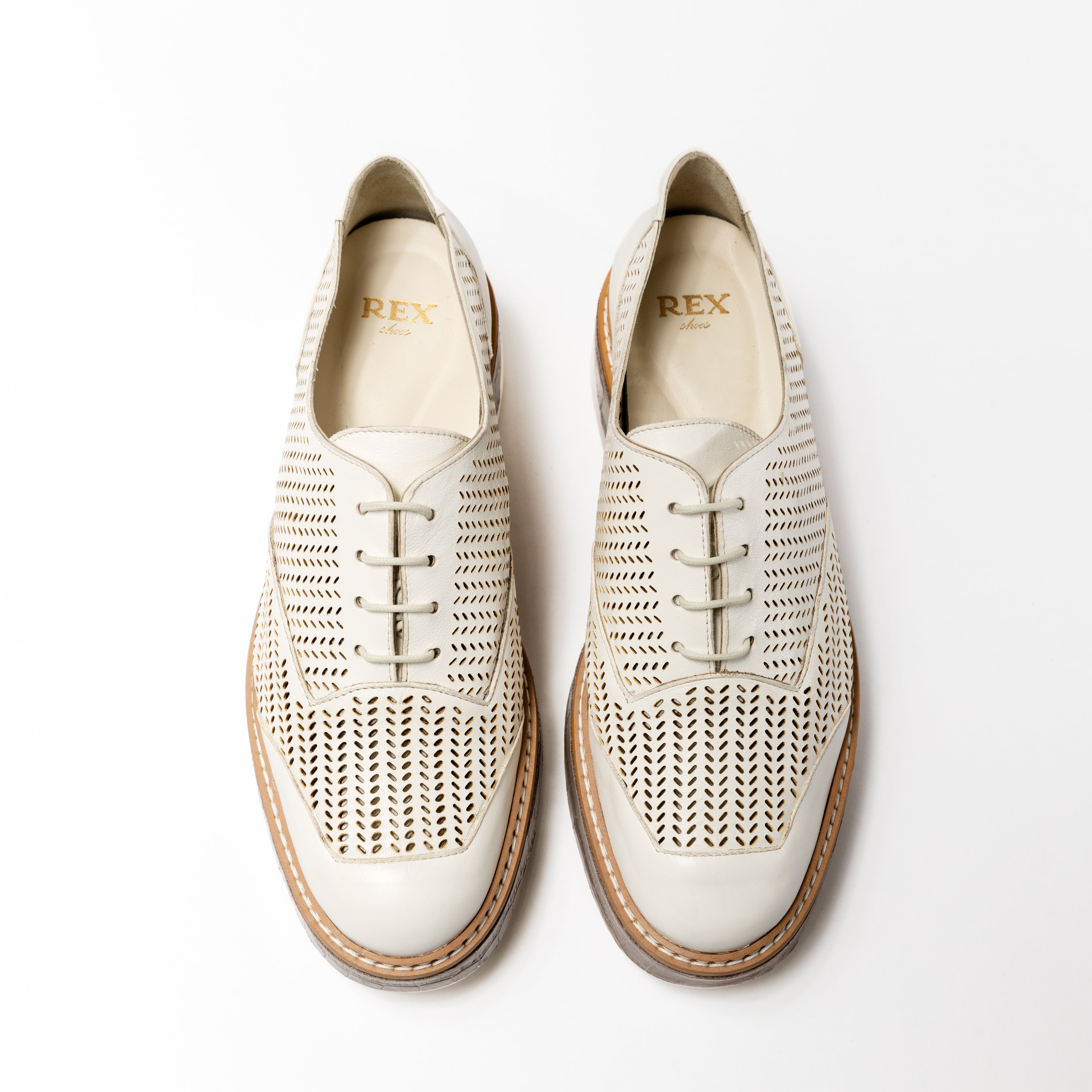Top-down view of the &#39;Liz&#39; Oxford shoes in Panna Leather, showcasing a crisp white perforated upper and lace-up design, with a classic brown welt and white sole.